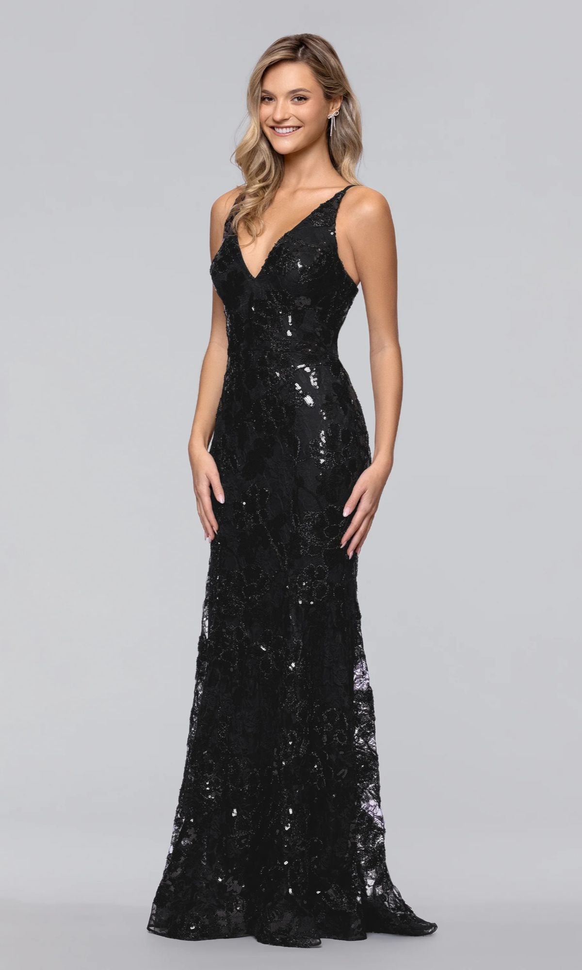 A woman wearing the Blondie Nites 5883BN long sequin-print prom dress with a V-neckline stands against a plain light gray background.